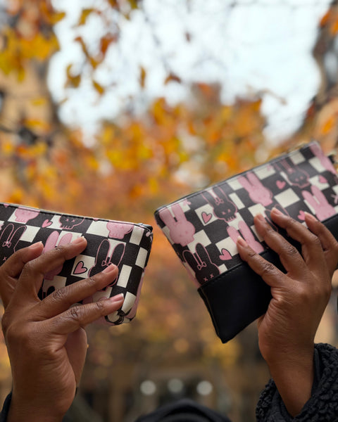 Two hands holding patterned wallets against a blurred autumnal background