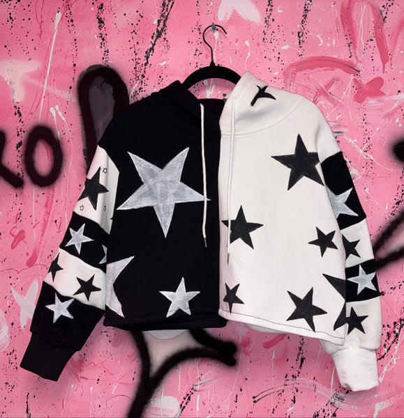 Black and white star-patterned sweatshirt on a hanger against a pink graffiti background